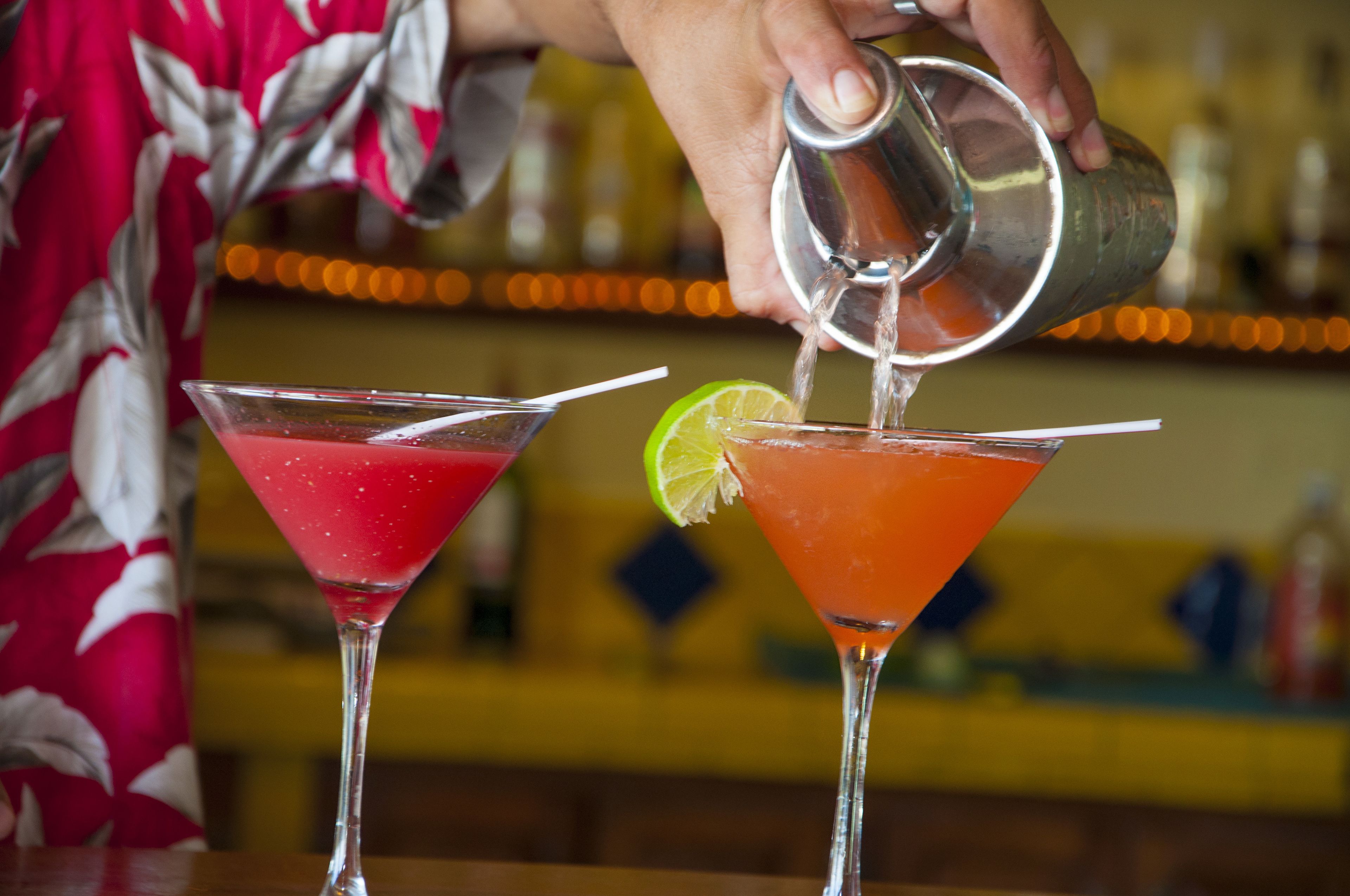 A person pouring a drink into a martini glass.