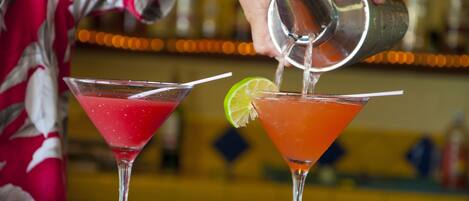 A person pouring a drink into a martini glass.
