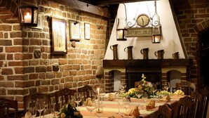 A warmly lit dining area with a brick wall, wooden furniture, and a fireplace. - Hotel Petite Fleur - Adults only (Torun)