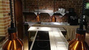 A kitchen with copper appliances, hanging pendant lights, and a brick wall. - Hotel Petite Fleur - Adults only (Torun)
