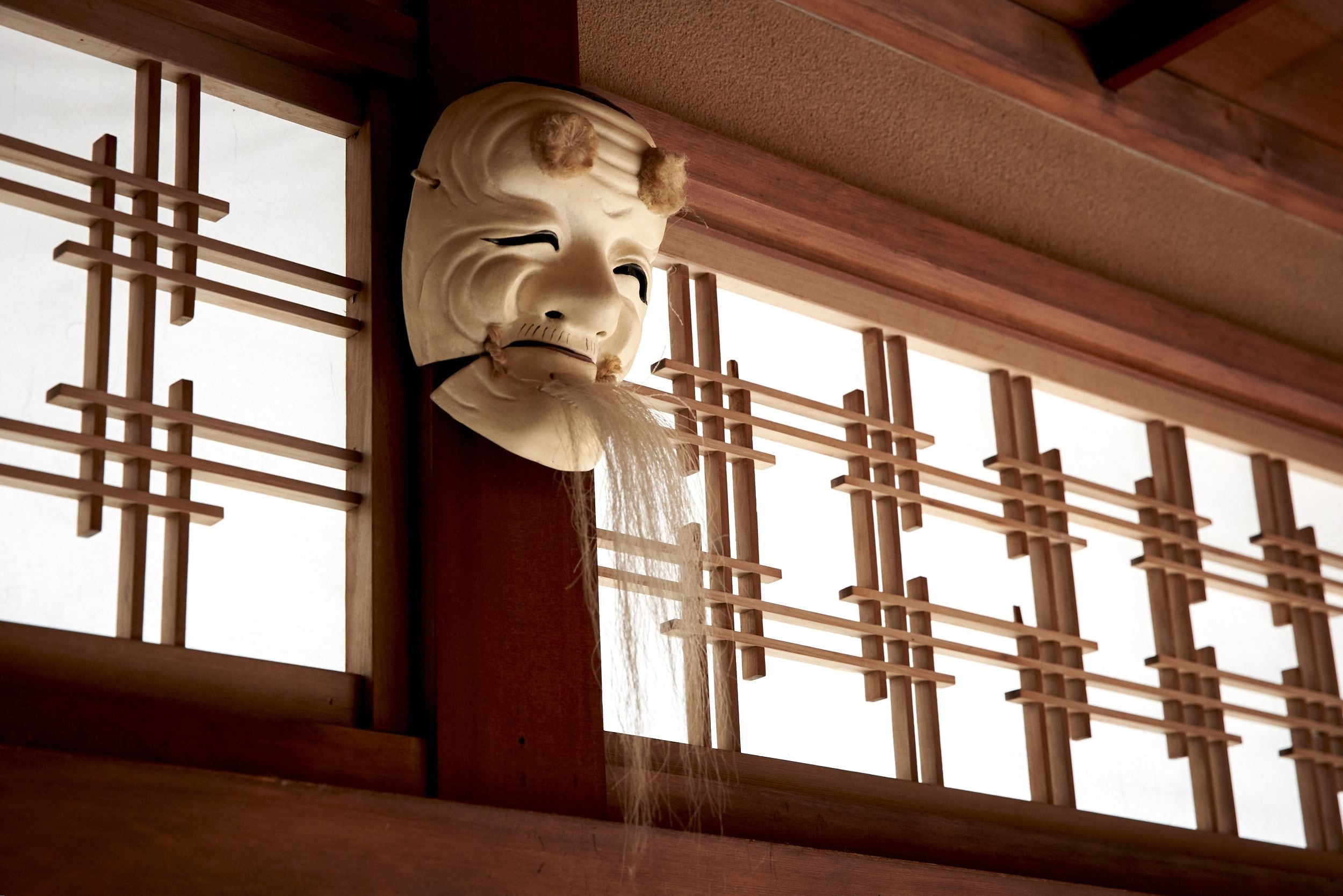 A traditional Japanese room with tatami flooring, a shoji screen, and a hanging shimenawa rope.