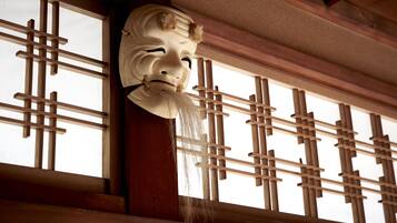 A traditional Japanese room with tatami flooring, a shoji screen, and a hanging shimenawa rope.