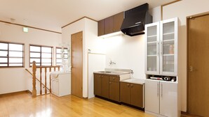 A kitchen with wooden cabinets, a black range hood, and a white refrigerator. - Hotobil (Nara)
