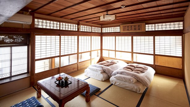 A traditional Japanese room with tatami flooring, a low wooden table, and a futon bed. - Hotobil (Nara)