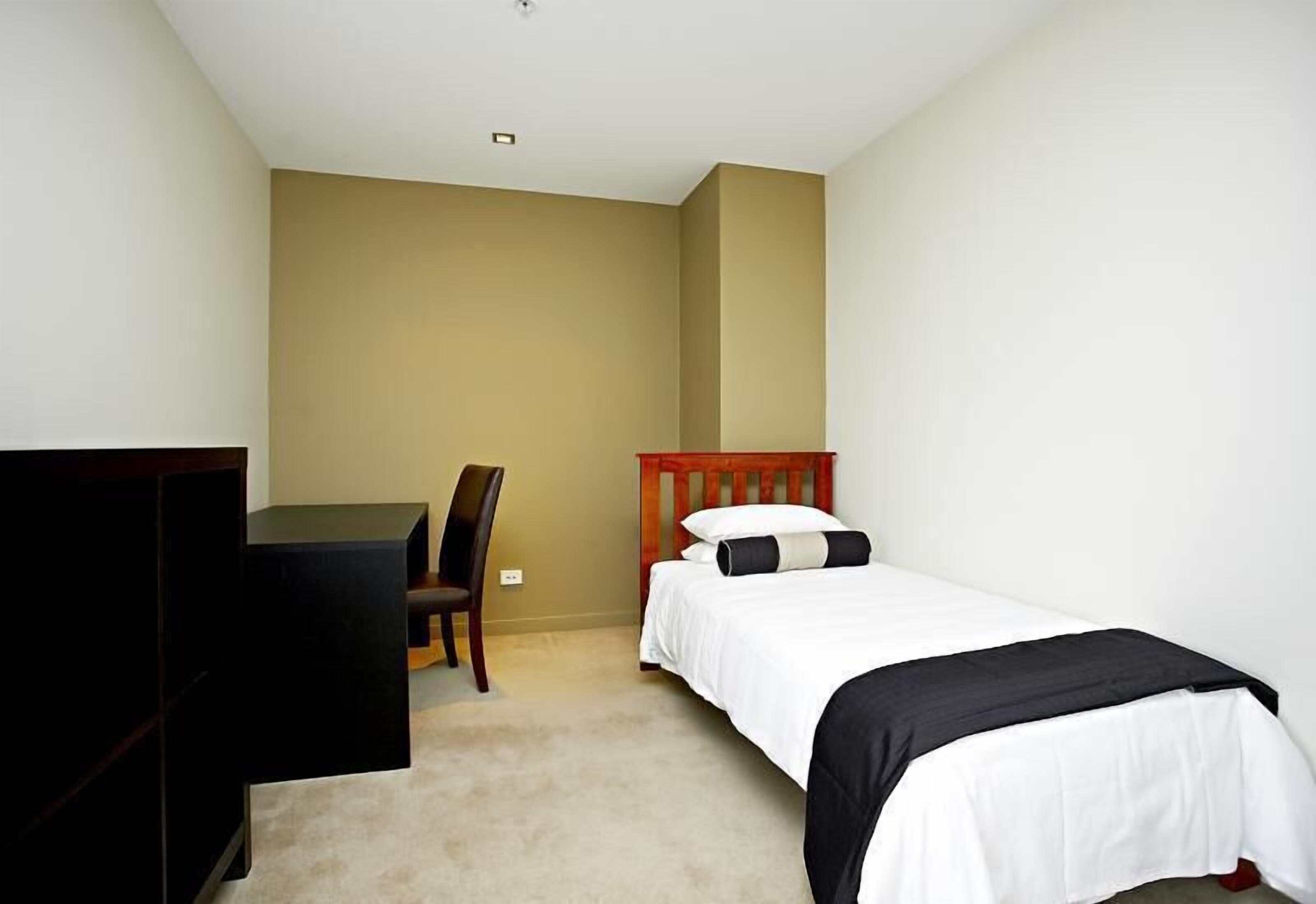 A bedroom with a bed, a desk, and a chair.