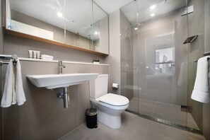 A modern bathroom with a glass shower enclosure, a white sink, and a toilet. - Astra Apartments - Docklands (Docklands)