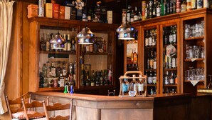 A bar area with wooden furniture, shelves stocked with liquor bottles, and hanging pendant lights. - Hotel Askania (Bad Wiessee)