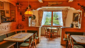 A wooden interior with a dining table and benches, a window with curtains, and various wall decorations. - Hotel Askania (Bad Wiessee)