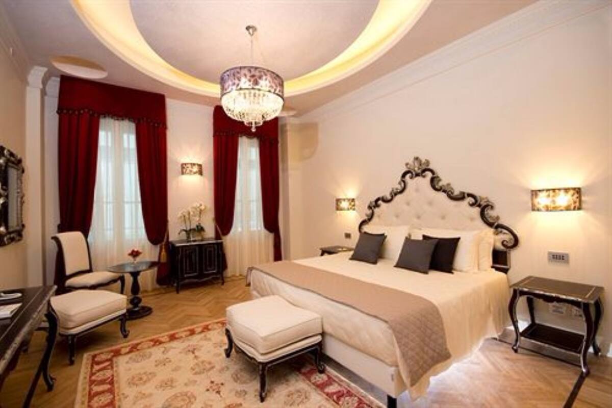 A spacious bedroom with a large bed, a chandelier, and a classic design.
