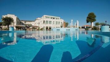 A swimming pool with clear blue water, surrounded by buildings and trees.