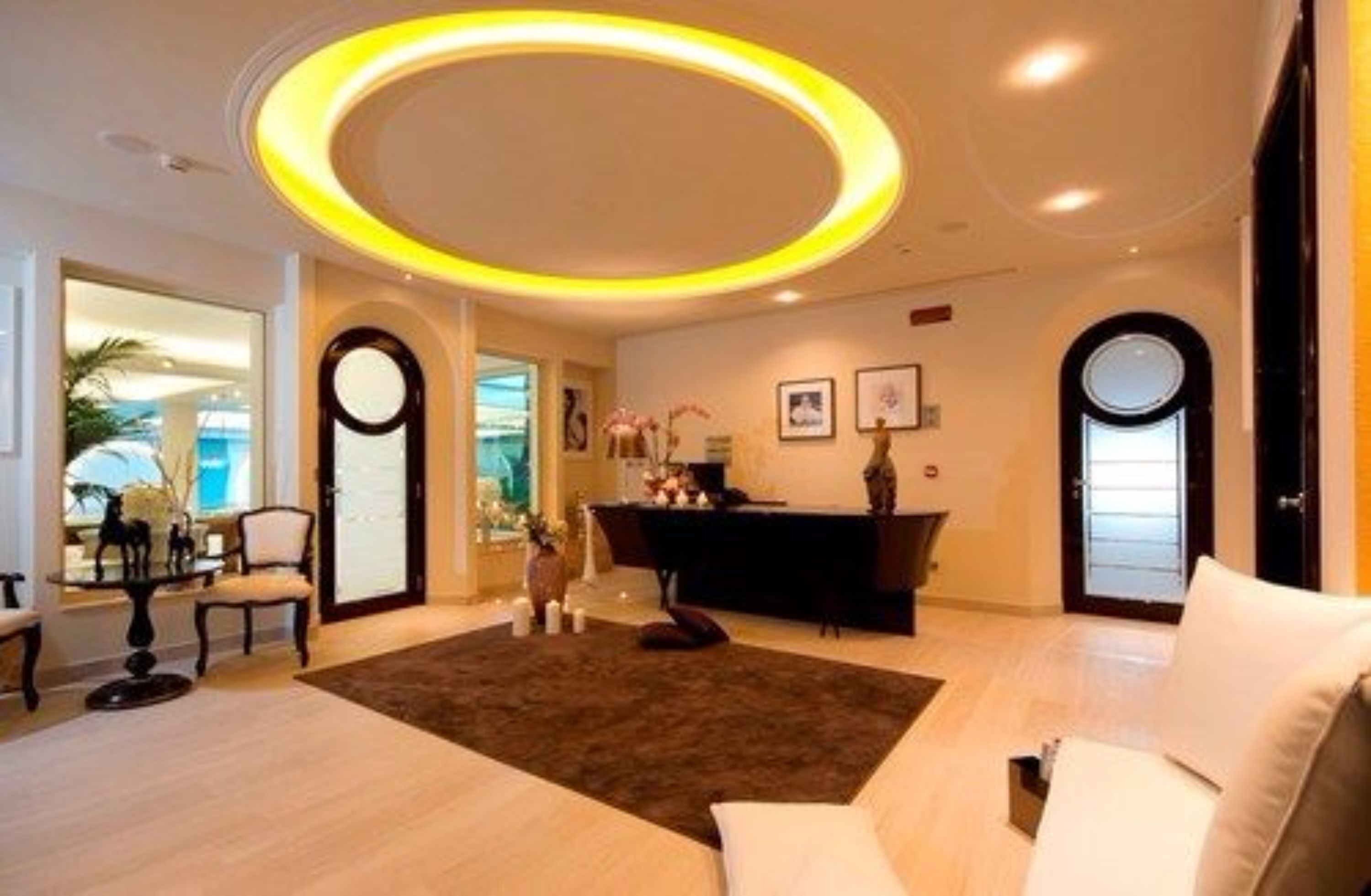 Una sala de estar moderna con una lámpara de techo circular, un sofá, una mesa de centro y un escritorio con una computadora.