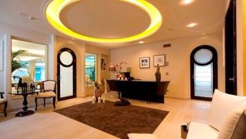 Una sala de estar moderna con una lámpara de techo circular, un sofá, una mesa de centro y un escritorio con una computadora.