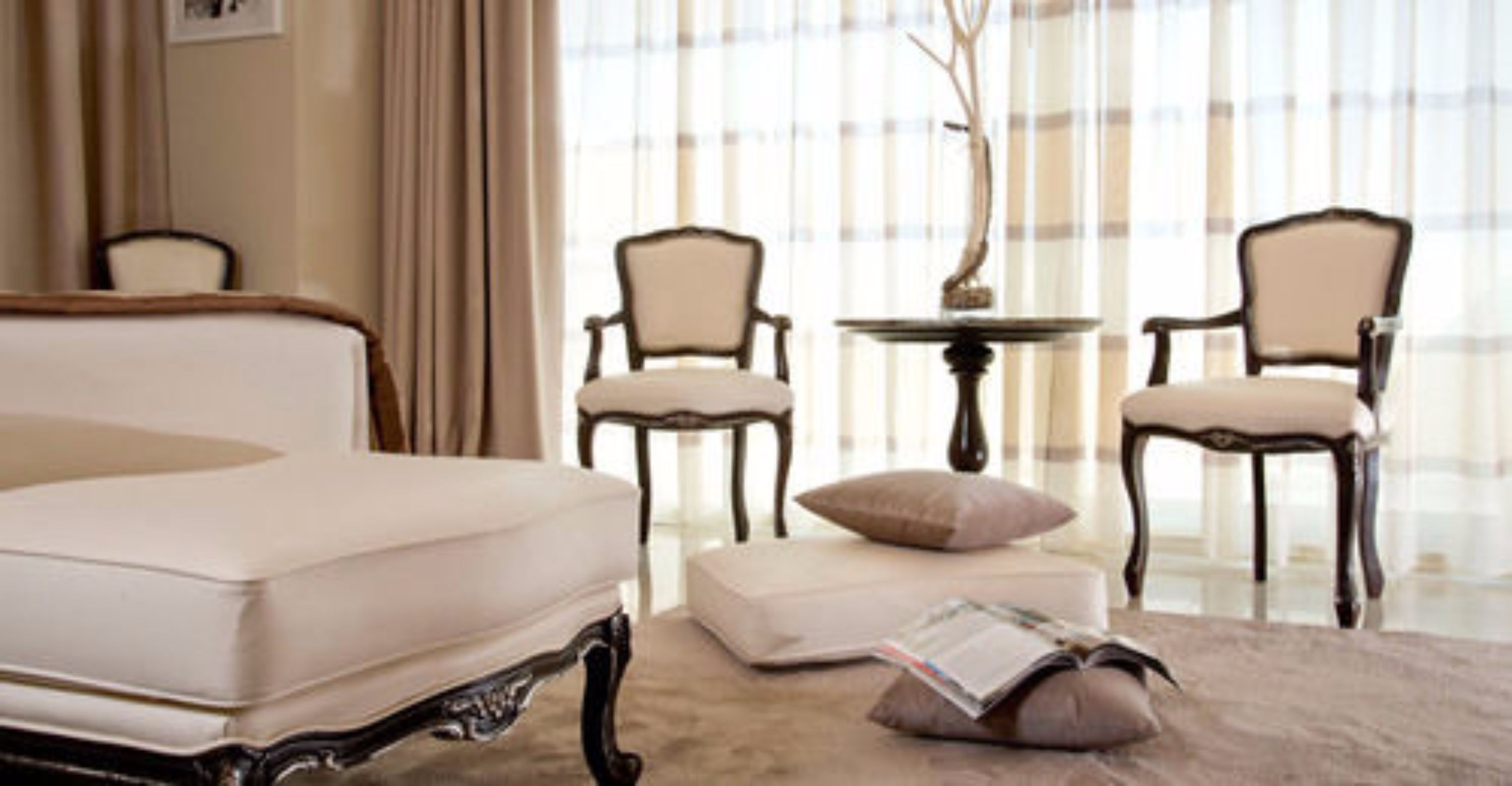 Une chambre à coucher avec un grand lit, deux chaises, une petite table et une fenêtre avec des rideaux.