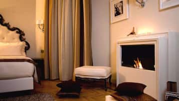 A bedroom with a bed, a nightstand, a fireplace, and a window with curtains.