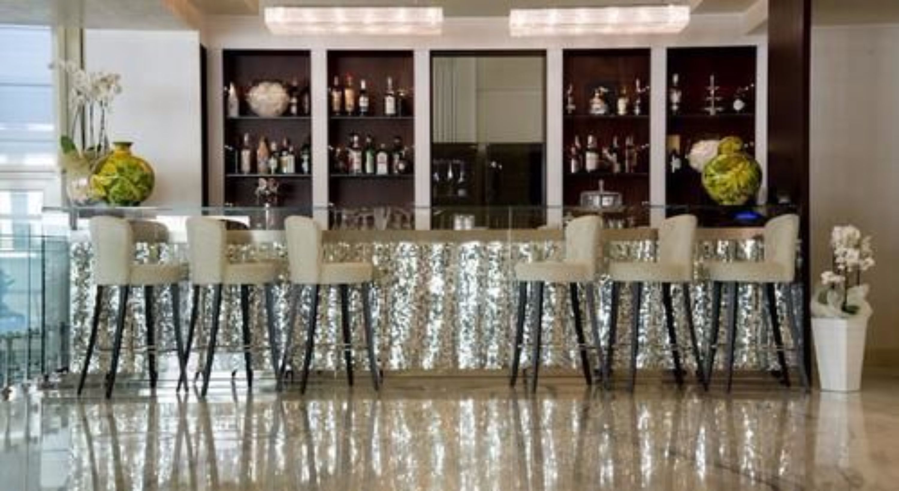 A bar area with mirrored backdrops, multiple shelves with bottles, and a reflective floor.