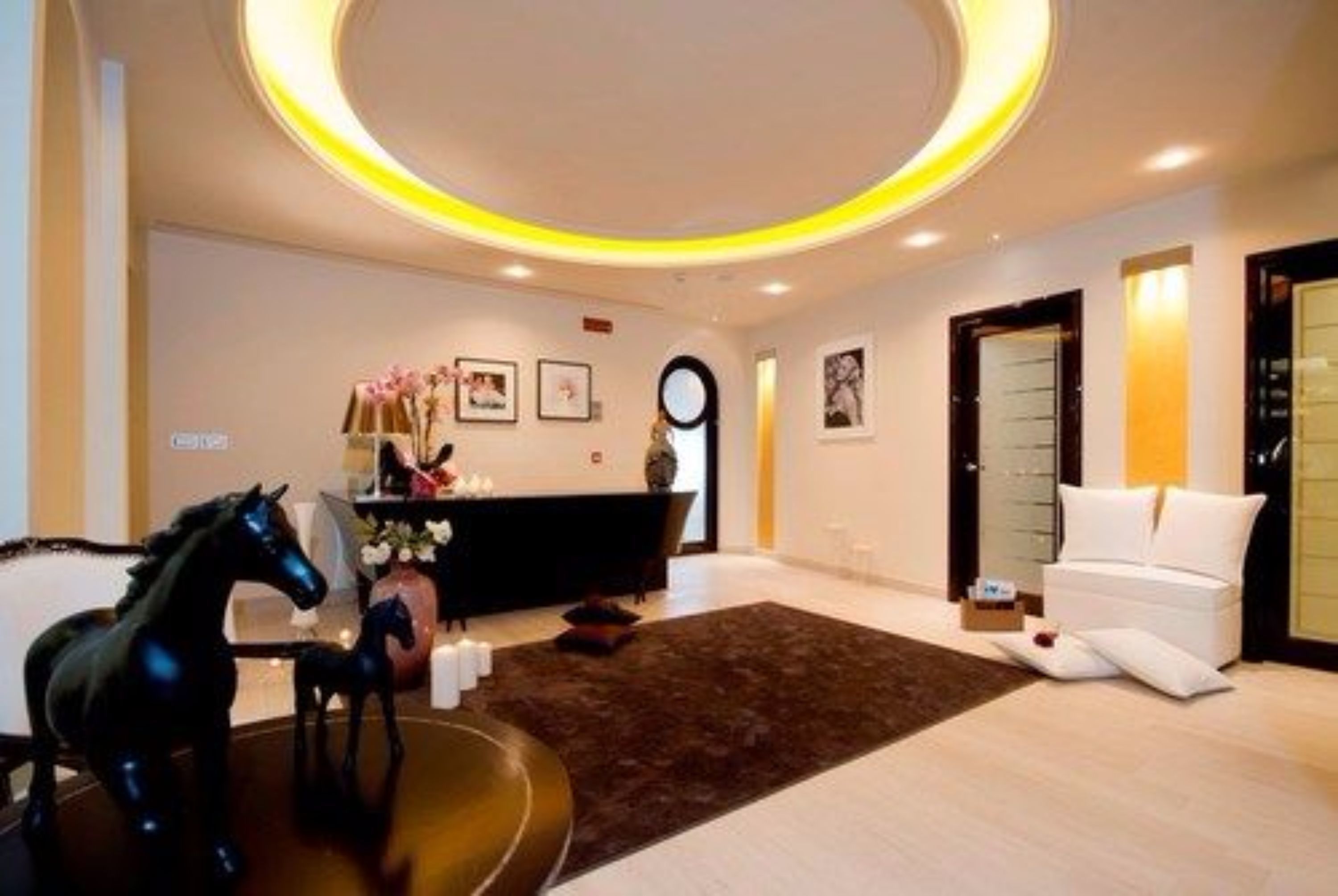 A modern hotel lobby with a reception desk, a black horse statue, a white sofa, and a brown rug.