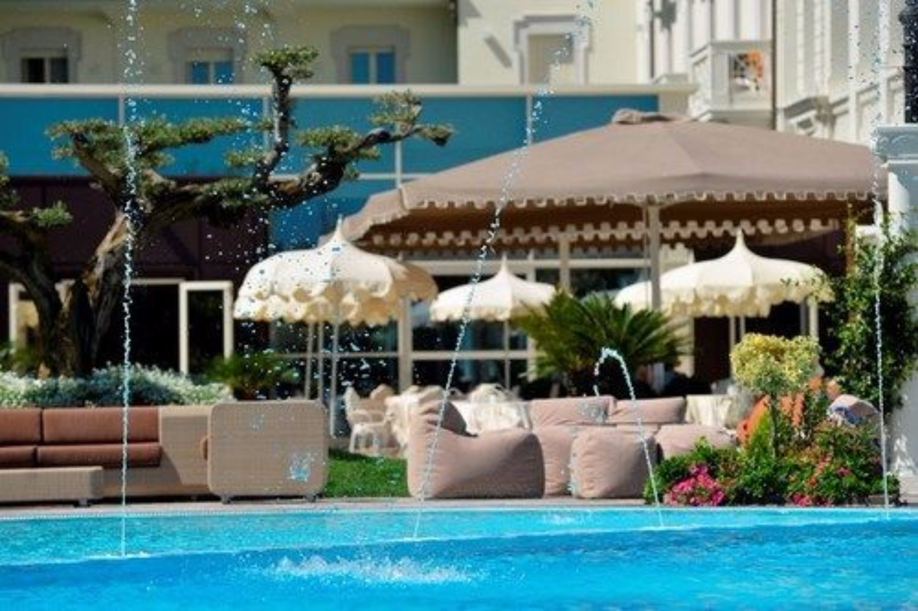Zona de piscina amb hidromassatges, gandules i ombrelles.
