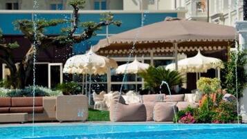 Zona de piscina amb hidromassatges, gandules i ombrelles.