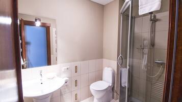 A bathroom with a sink, toilet, and glass-enclosed shower area.