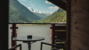 A table and chairs in a room with a view of a lake and mountains.