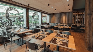 A modern restaurant with multiple dining areas, large windows, and contemporary interior design.