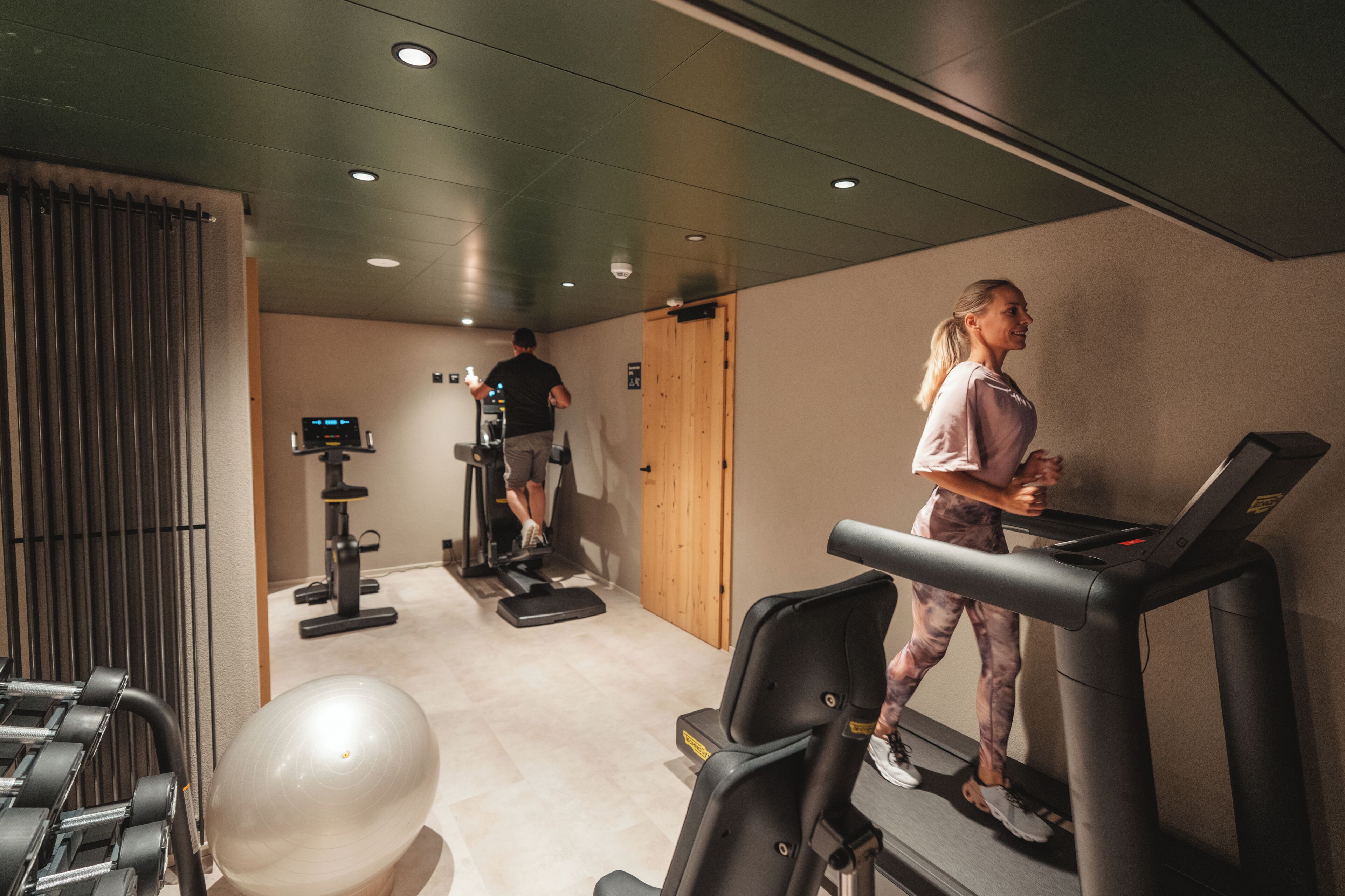 Un gimnasio con cintas de correr, una bicicleta estática y pesas sueltas.