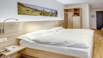Ein modernes Hotelzimmer mit einem hölzernen Bett, einem fest installierten Telefon und einem Gemälde einer Berglandschaft.