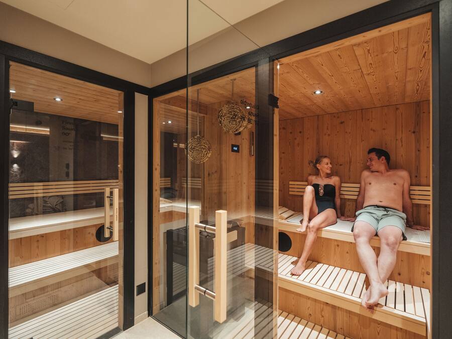 Una sala de sauna con bancos de madera y paredes de vidrio.