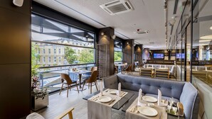 Un restaurante moderno con terraza, amplios ventanales y vistas a edificios.