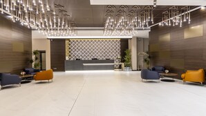 Un vestíbulo amplio con muebles modernos, un mostrador de recepción e iluminación decorativa.