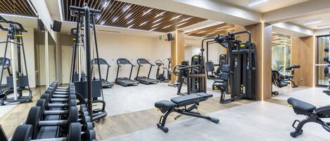 A modern gym with various exercise equipment, including treadmills, weight machines, and free weights.