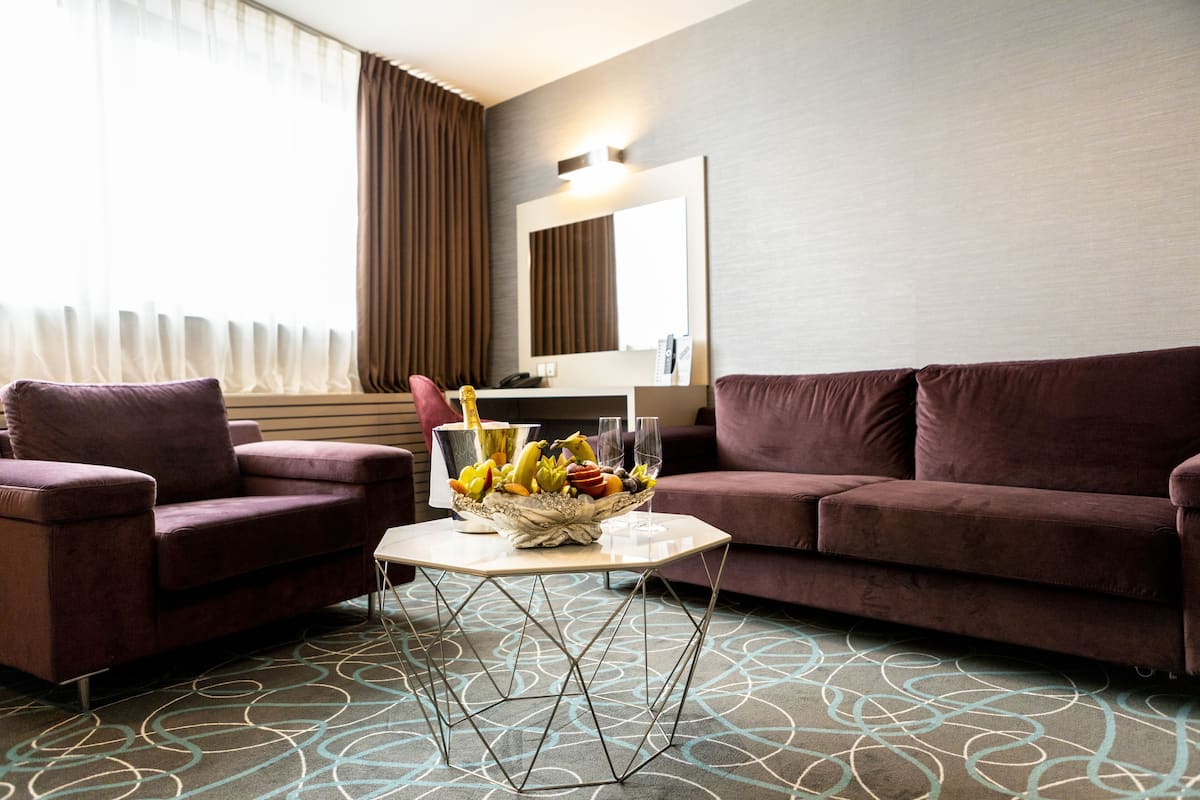 A modern living room with a brown sofa, a matching armchair, and a coffee table with a fruit bowl.