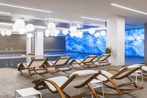 Una piscina techada, sillones reclinables de piscina