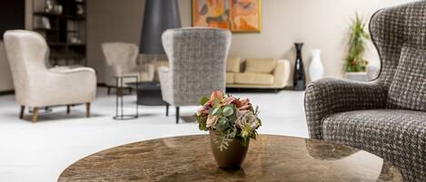 A modern living room with a round coffee table, a sofa, and a chair. There is a bookshelf and a painting on the wall.