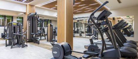 Un gimnasio con varios equipos de ejercicio, paneles de techo de madera y un espejo grande.