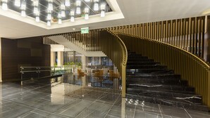 Un interior moderno con una escalera curva, suelo de mármol negro reflectante e iluminación empotrada en el techo.