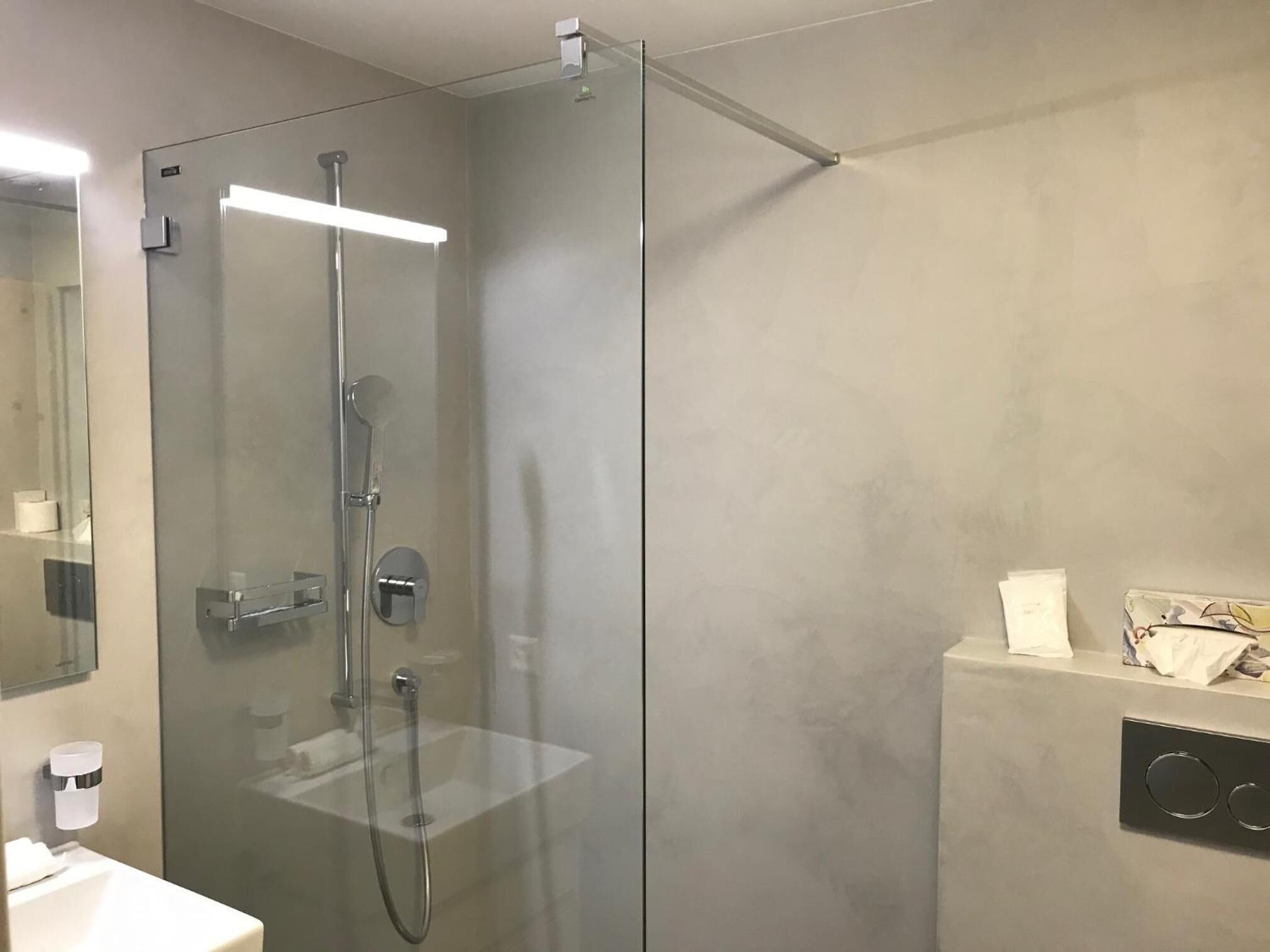 Un baño moderno con ducha de vidrio, lavamanos blanco y espejo.