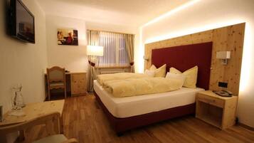 A hotel room with a large bed, bedside tables, a desk, and a television.