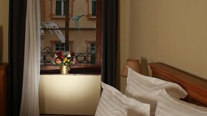 A hotel room with a bed, a window with curtains, a vase with flowers, and a lamp. - Hotel Sighisoara (Sighisoara)