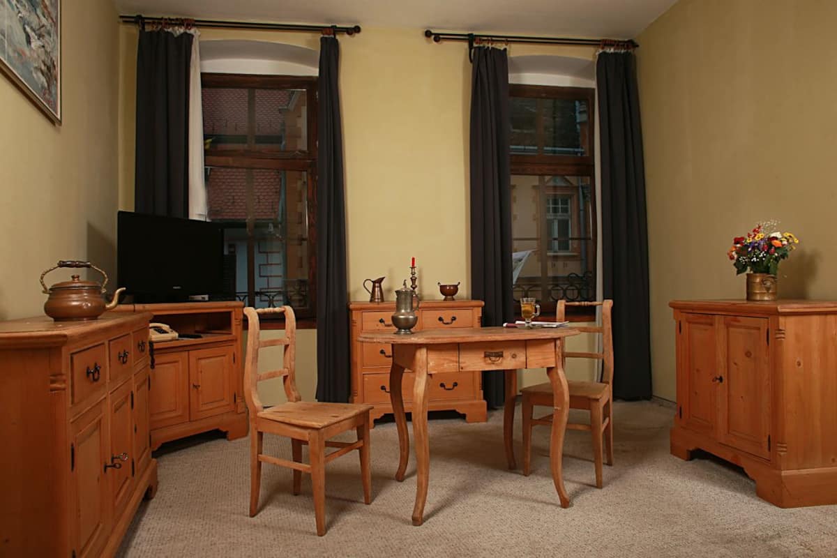 A room with wooden furniture, a television, and a window with curtains.