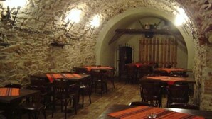 A rustic dining area with stone walls and wooden tables, each with a red placemat. - Hotel Sighisoara (Sighisoara)