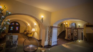 A warmly lit interior with arched doorways, a staircase, and a reception area with a bulletin board. - Hotel Sighisoara (Sighisoara)