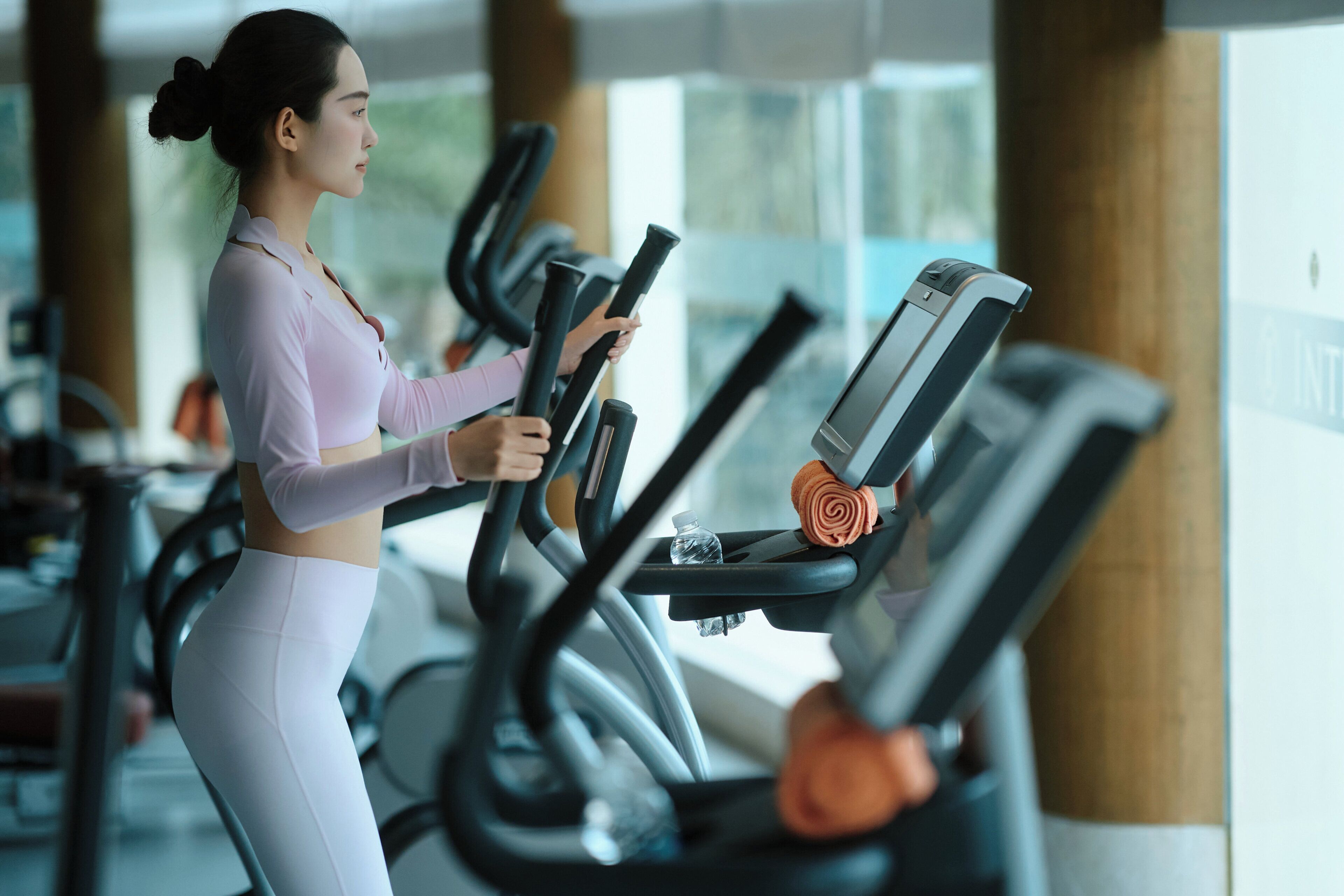 A gym with exercise equipment and a person using a treadmill.