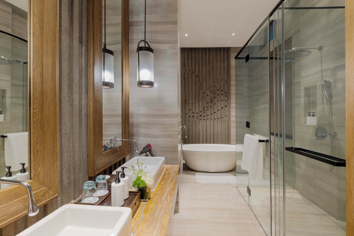 Ein modernes Badezimmer mit einer großen Badewanne, einer Duschkabine und einem Waschtisch mit Marmorplatte.