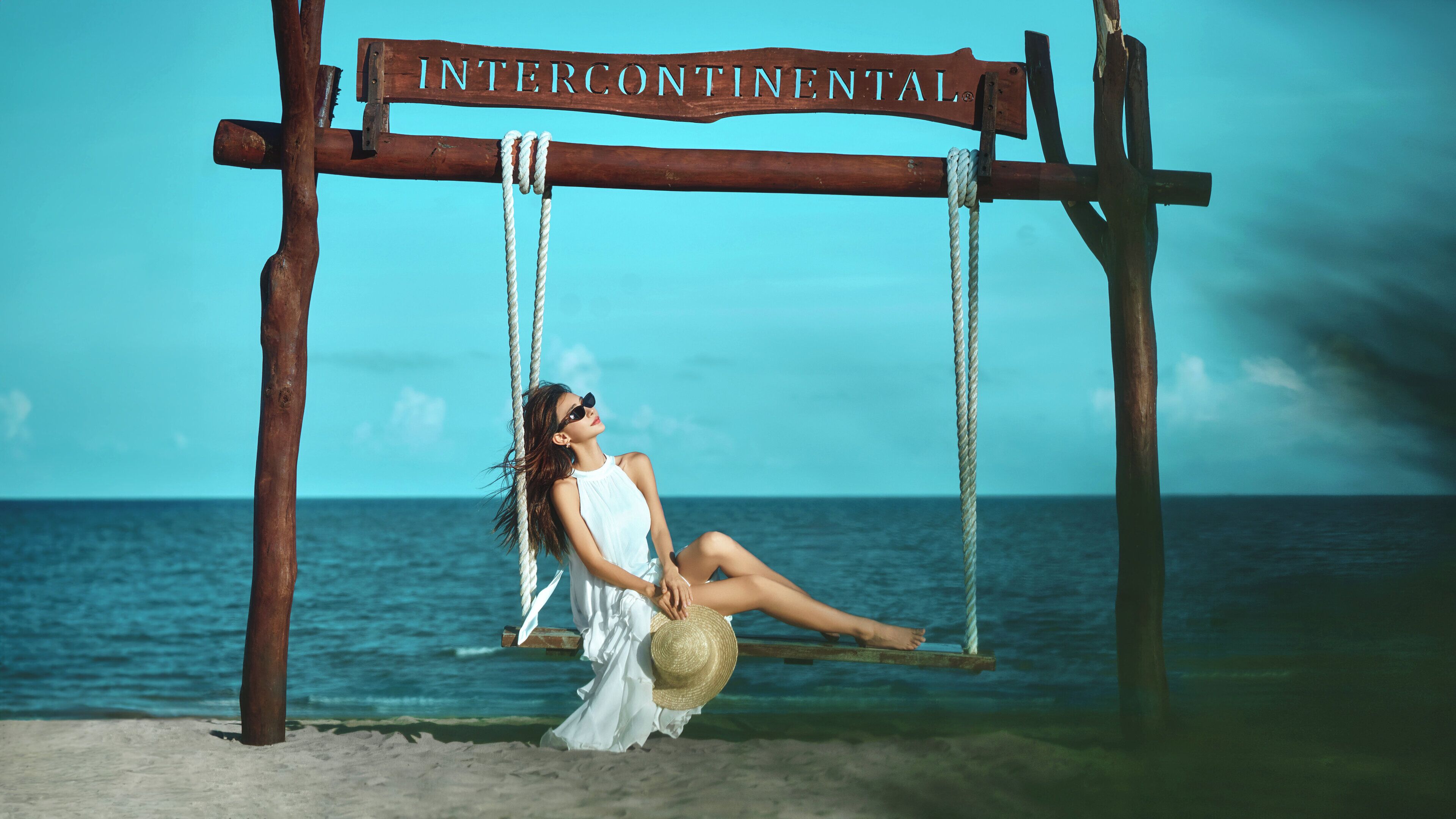 A wooden swing set labeled 'INTERCONTINENTAL' with a person sitting on it.