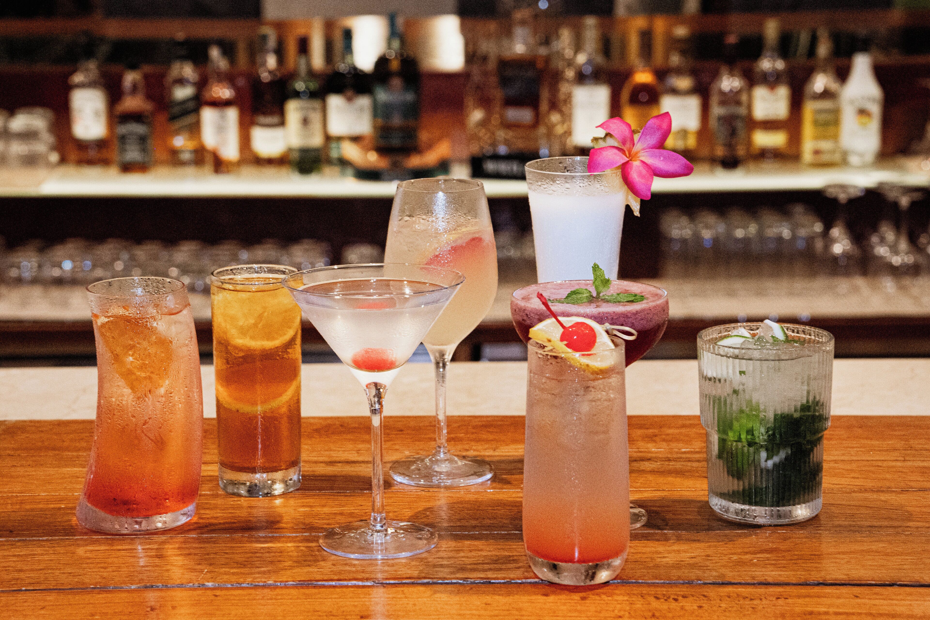 Eine Bar mit verschiedenen Cocktails und einer Auswahl an Flaschen im Hintergrund.