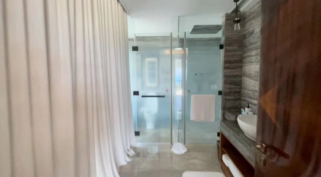A modern bathroom with a glass shower enclosure, a wooden vanity, and a large mirror.