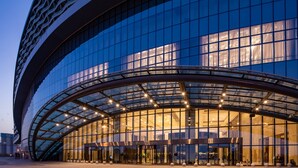 Un hôtel moderne doté d’une façade en verre incurvée, d’une entrée couverte et d’une porte tournante bien visible.