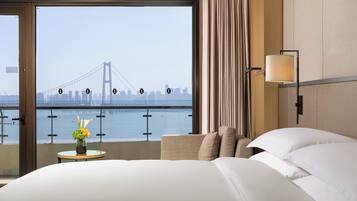 Une chambre d’hôtel dotée d’une grande fenêtre donnant sur un pont et sur le panorama de la ville.