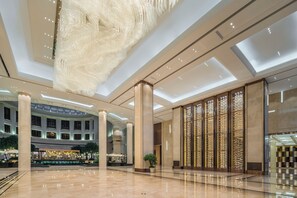 A spacious lobby with a high ceiling, large columns, and a central fountain.